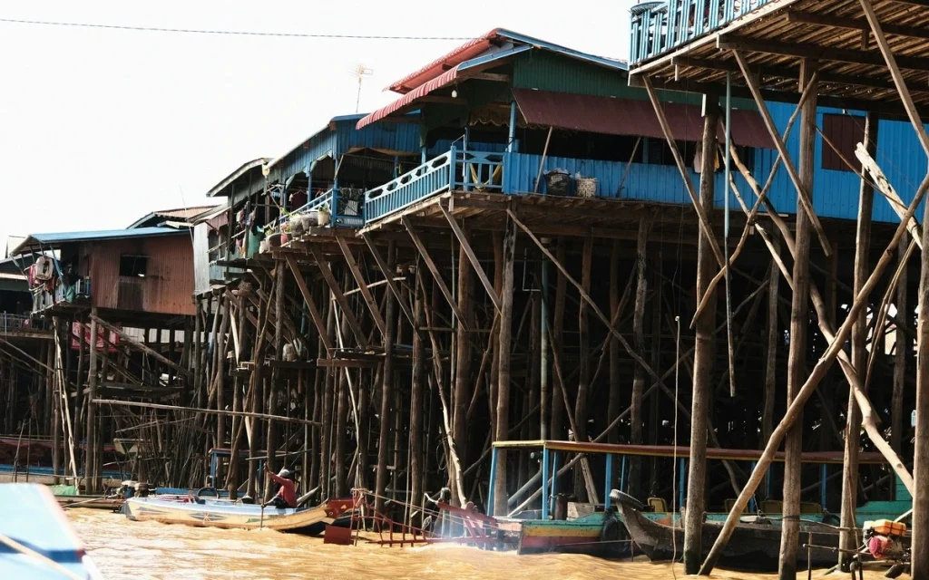 Passengers travelling by boat past traditional stilt houses on Tonlé Sap Lake, Cambodia.